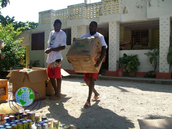 Two volunteers carrying boxes of donated food and supplies in Haiti